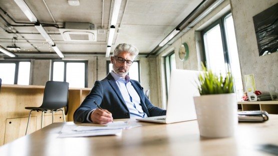 Mature businessman with laptop in the office